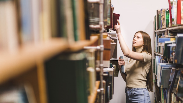 A picture of a woman looking for a book in the library